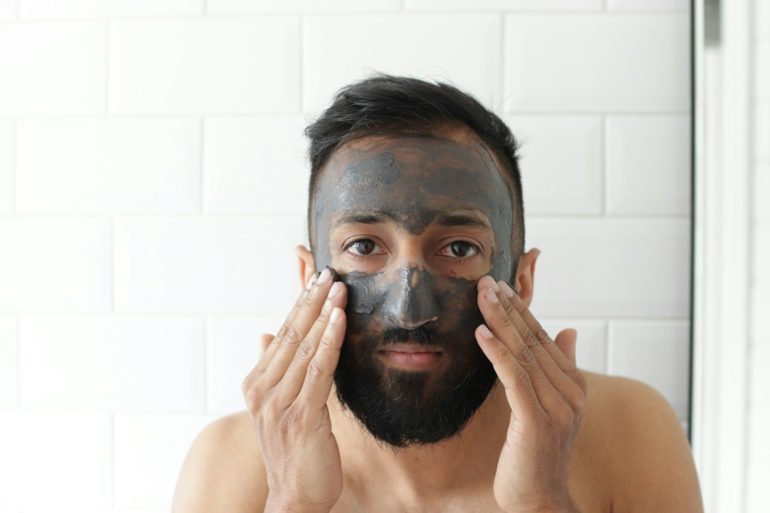 topless man covering face with white powder