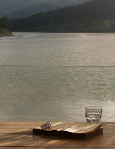 clear drinking glass on brown wooden table near body of water during daytime